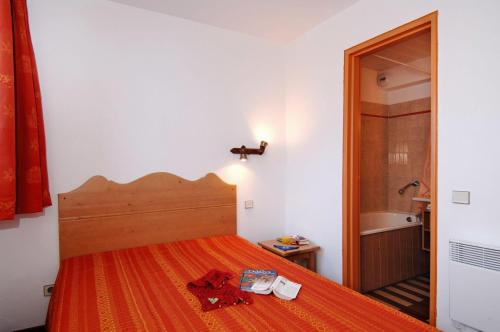 蒂涅Résidence Odalys Le Hameau du Borsat的一间卧室配有一张带橙色床罩的床