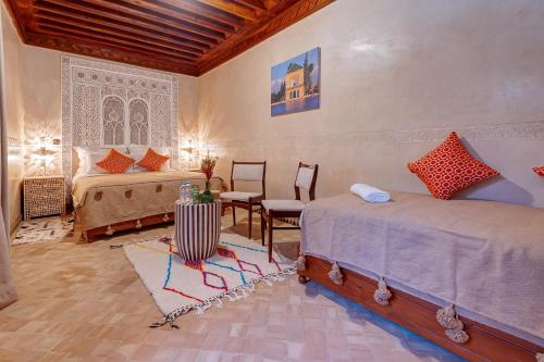 马拉喀什Riad Amalia的一间卧室配有两张床和一张桌子及椅子