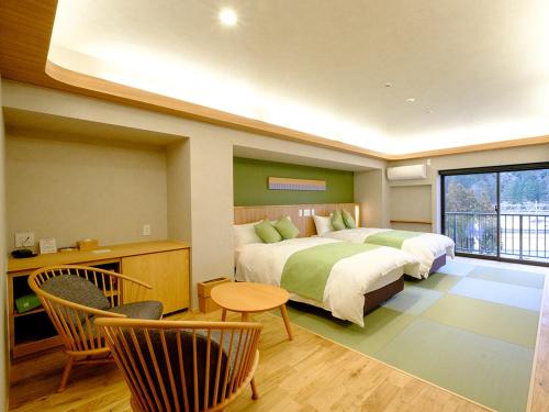 美作汤乡大酒店的一间卧室配有两张床和一张桌子及椅子
