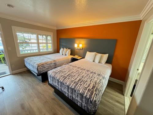 蒙特雷帕德里奥克斯酒店的酒店客房设有两张床和橙色的墙壁。