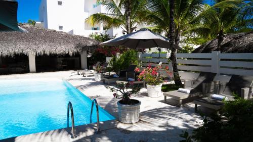 蓬塔卡纳Boutique Hotel Las Flores Punta Cana的一座带椅子和遮阳伞的游泳池位于大楼旁