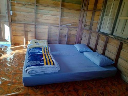 Ban NongbouaShared Happy Farm的木制客房内的一张蓝色大床