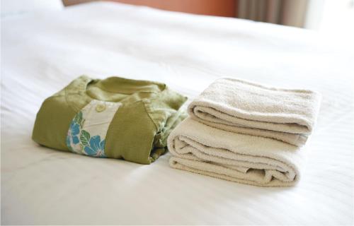 北中城村EM Wellness Kurashinohakko Lifestyle Resort的床上的一大堆毛巾