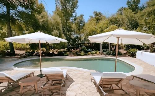圣埃乌拉利亚La Finca Agroturismo Can Bet的庭院内一个带椅子和遮阳伞的游泳池