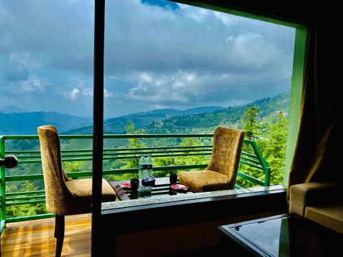 西姆拉Aachman Nature Valley Resort Shimla的美景阳台配有两把椅子和一张桌子