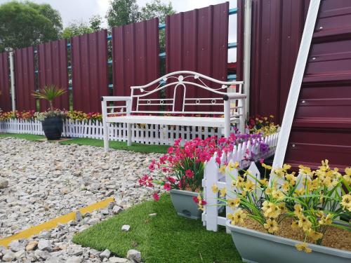 甘榜甘马挽Red Triangle Cottage Roomstay的花园里的长凳,花朵和围栏
