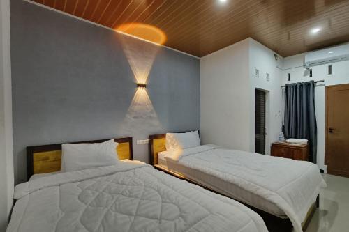 棉兰OYO 93709 Rose Inn 2的卧室配有两张床,墙上有灯