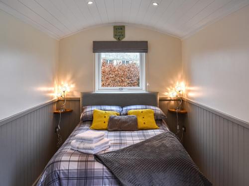 GilcruxGreengill Farm Shepherds Hut- Ukc3632的一间卧室配有一张带黄色枕头的床和一扇窗户