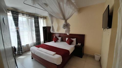 内罗毕Epitome Times Hotel的一间卧室配有一张带红色枕头的大床