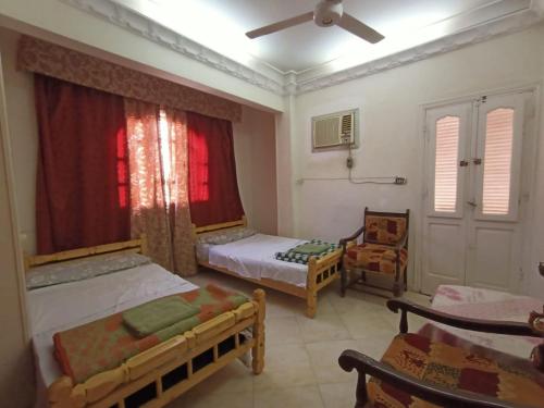 阿斯旺david hostel的一间卧室设有两张床、一把椅子和一个窗户。