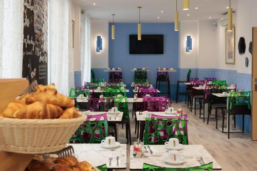 尼斯Hôtel Byakko Nice的配有桌椅和一篮面包的用餐室
