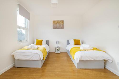 雷纳姆Heads-On-Beds Rainham Essex - 4Bedrooms with Garden的配有白色墙壁和木地板的客房内的两张床