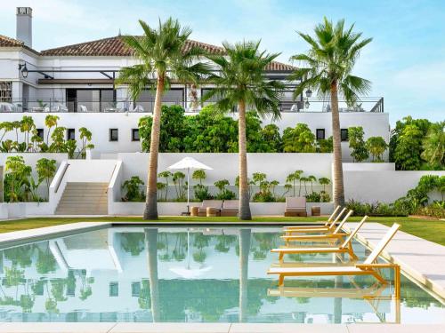 索托格兰德SO/ Sotogrande Spa & Golf Resort Hotel的游泳池的形象,游泳池的椅子和棕榈树