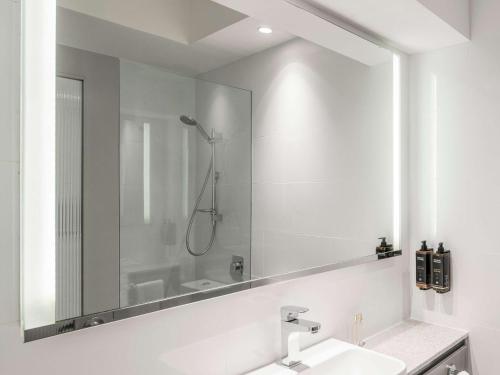 悉尼Novotel Sydney City Centre的一间带大镜子和盥洗盆的浴室