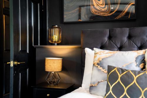 ShenstoneGorgeous 6 Bed House - Hot Tub - Wifi & Large Garden - Lichfield 40ST的一间卧室配有一张带黑色床头板和灯的床。