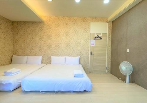 Hsia-shih-pi逢甲馨宿的一间卧室设有两张床、风扇和一扇门