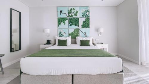 塞图巴尔里约艺术酒店的白色卧室配有一张带绿毯的大床