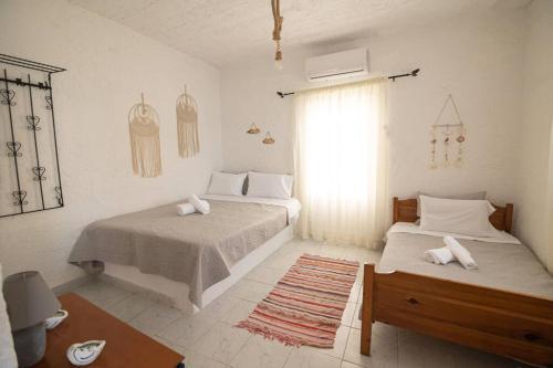 ParánimfoiBeachfront Lovely Small House on the Sea的一间白色卧室,配有两张床和窗户