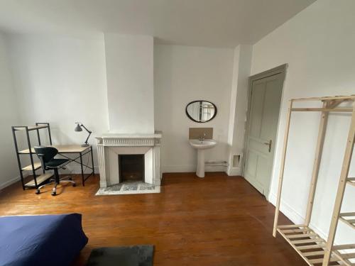 杜埃Ancienne maison de maitre的客房设有壁炉、桌子和书桌。