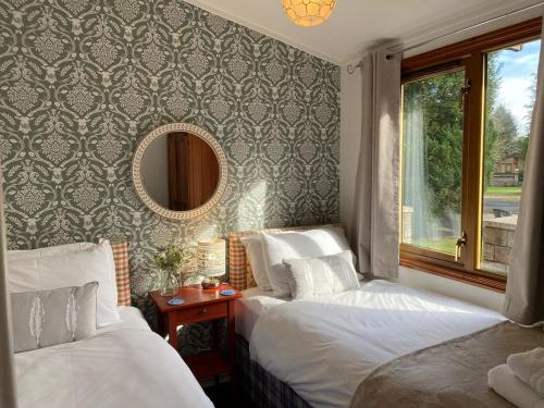 巴洛赫Walled Garden Lodges Loch Lomond的配有镜子的酒店客房内的两张床