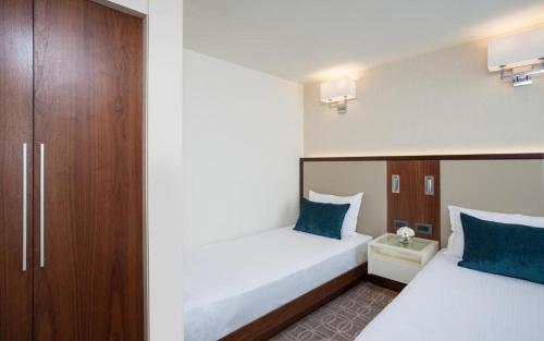 埃拉特Royal Beach eilat的两张位于酒店客房的床,配有蓝色枕头