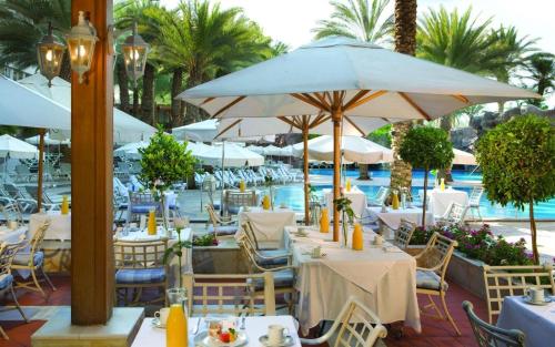 埃拉特Royal Beach eilat的池畔餐厅,配有桌子和遮阳伞