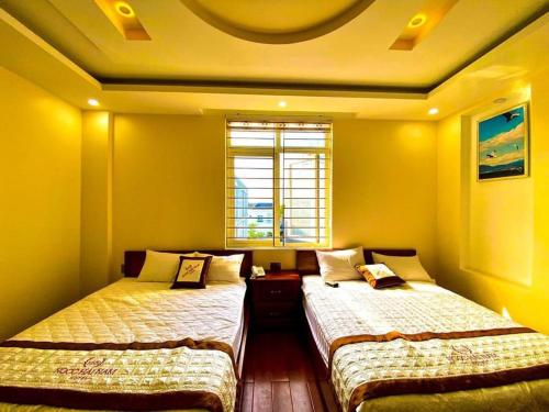 Nhơn TrạchNgọc Hải Nam Hotel - Khách Sạn Nhơn Trạch的配有两张床的客房,设有黄色的墙壁和窗户