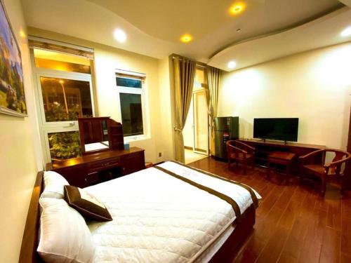 Nhơn TrạchNgọc Hải Nam Hotel - Khách Sạn Nhơn Trạch的一间卧室配有一张床、一张书桌和一台电视