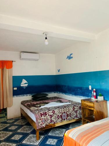 El Paredón Buena VistaCuarto Cactus的一间卧室设有两张床和蓝色的墙壁