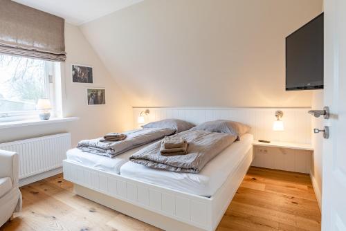 AlkersumWhite House Ferienwohnung 2的卧室配有白色床和平面电视