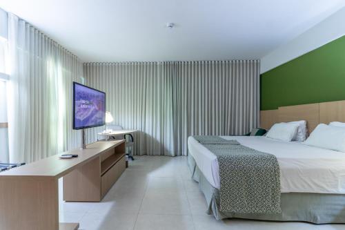 萨尔瓦多Sotero Hotel by Castelo Itaipava的配有一张床和一台平面电视的酒店客房