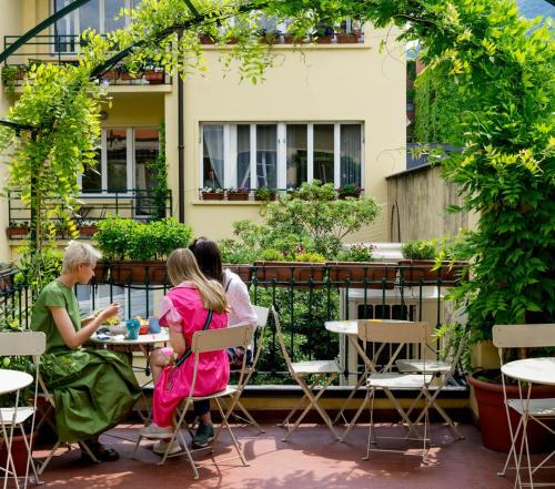 科莫科莫湖贝洛旅舍的三人坐在庭院的桌子上