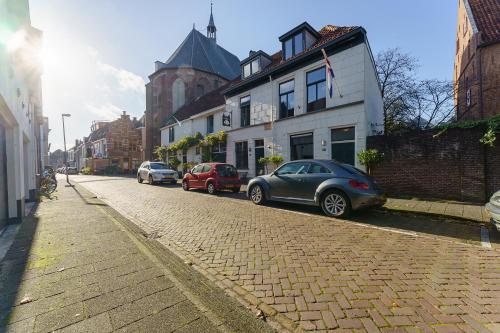 坎彭De Stadsboerderij的一条鹅卵石街道,汽车停在建筑前