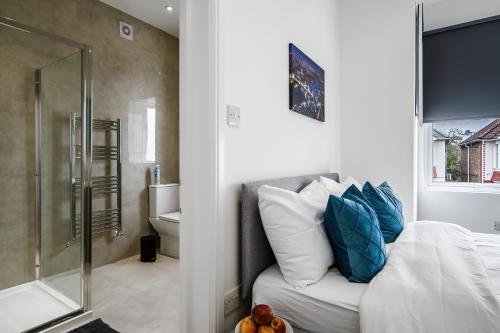 伦敦Modern Studio Rooms in Wembley的一间卧室设有一张床和一个玻璃淋浴间