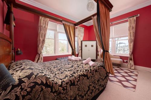 伊尔弗勒科姆Westwell Hall的一间卧室设有一张带红色墙壁的大床
