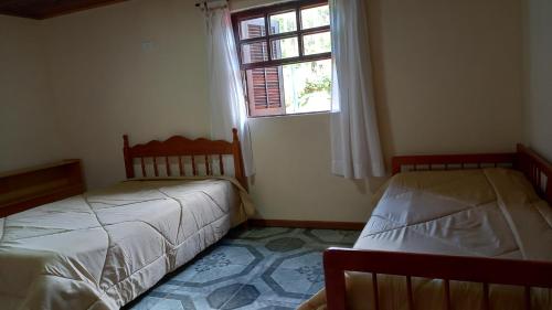 坎波斯杜若尔当Casa boa vista的一间卧室设有两张床和窗户。