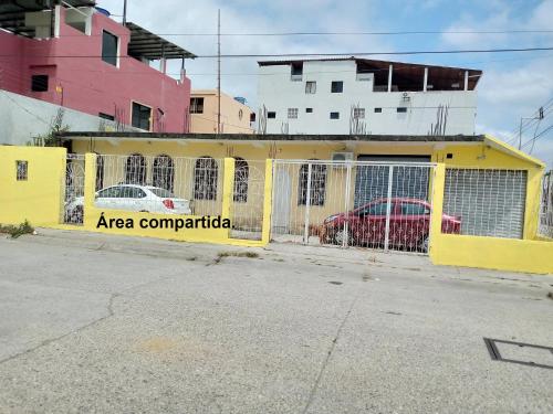 瓜亚基尔Acuarela del Rio H#1 Cerca Terminal Terrestre Habitación privada con baño的黄色围栏,两辆汽车停在后面