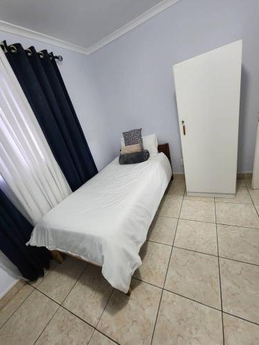 OngwedivaElina Self catering的小卧室配有一张带蓝色窗帘的床