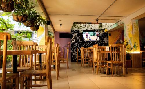 麦德林Green Hotel Medellin的餐厅设有木桌、椅子和电视