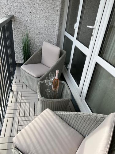 奥本Glenshellach Apartment Oban的阳台配有椅子和一张带一瓶酒的桌子。