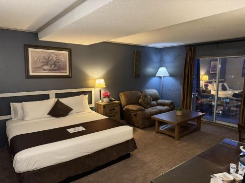 弗农Divya Sutra Plaza and Conference Centre, Vernon, BC的配有一张床和一把椅子的酒店客房