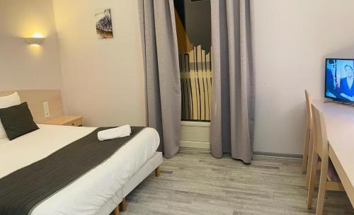 埃苏瓦Hôtel Les Demoiselles的一间卧室设有一张床、一台电视和一个窗口。