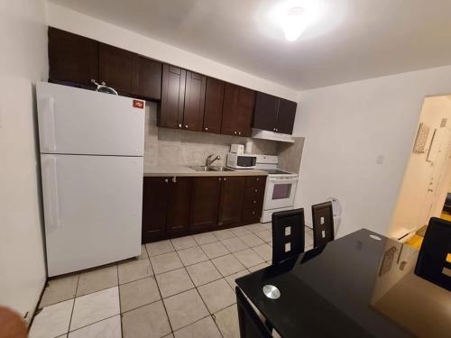 蒙特利尔425$ 7nights // Full Kitchen // Room B的厨房配有白色冰箱和木制橱柜。