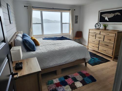 特威林盖特Seaclusion Twillingate的一间卧室配有一张带窗户和梳妆台的床