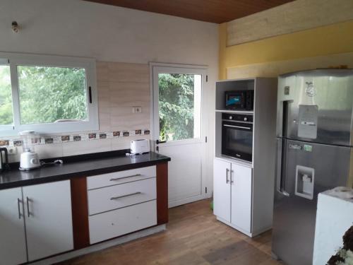 梅塞德斯Casa de Campo La Querencia的厨房配有白色橱柜和不锈钢冰箱
