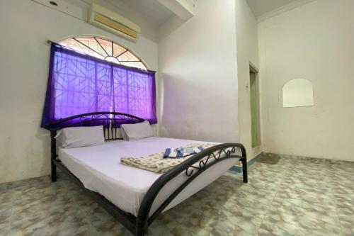 BagamOYO 93781 Hotel California 2的一间卧室配有一张带紫色窗户的床