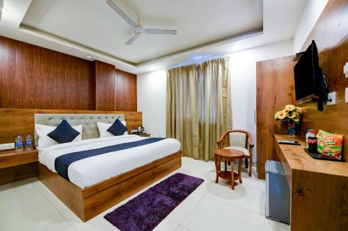 新德里Hotel Grand Qubic Near Delhi Airport的一间卧室配有一张床、一张书桌和一台电视