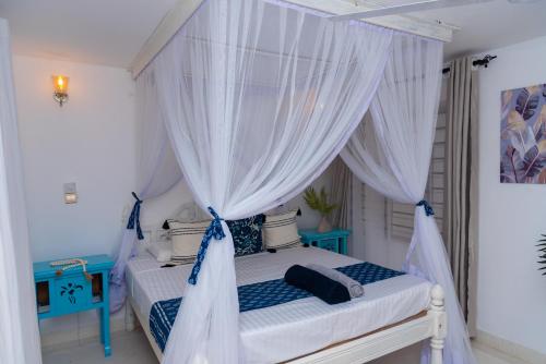 马林迪Malindi Palm Villa- Harbour Key Cottages, Villa 16, Silver Sands Road的卧室配有带白色窗帘的天蓬床