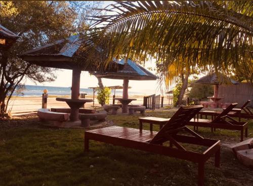 锡基霍尔D's Oceanview Beach Resort的海滩上的一组野餐桌和遮阳伞