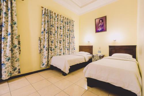 棉兰PIA Hotel Medan的配有窗帘的客房内的两张床
